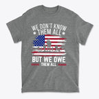 We Don't Know Them All But We Owe Them All On American Flag design t-shirt on gray fabric.