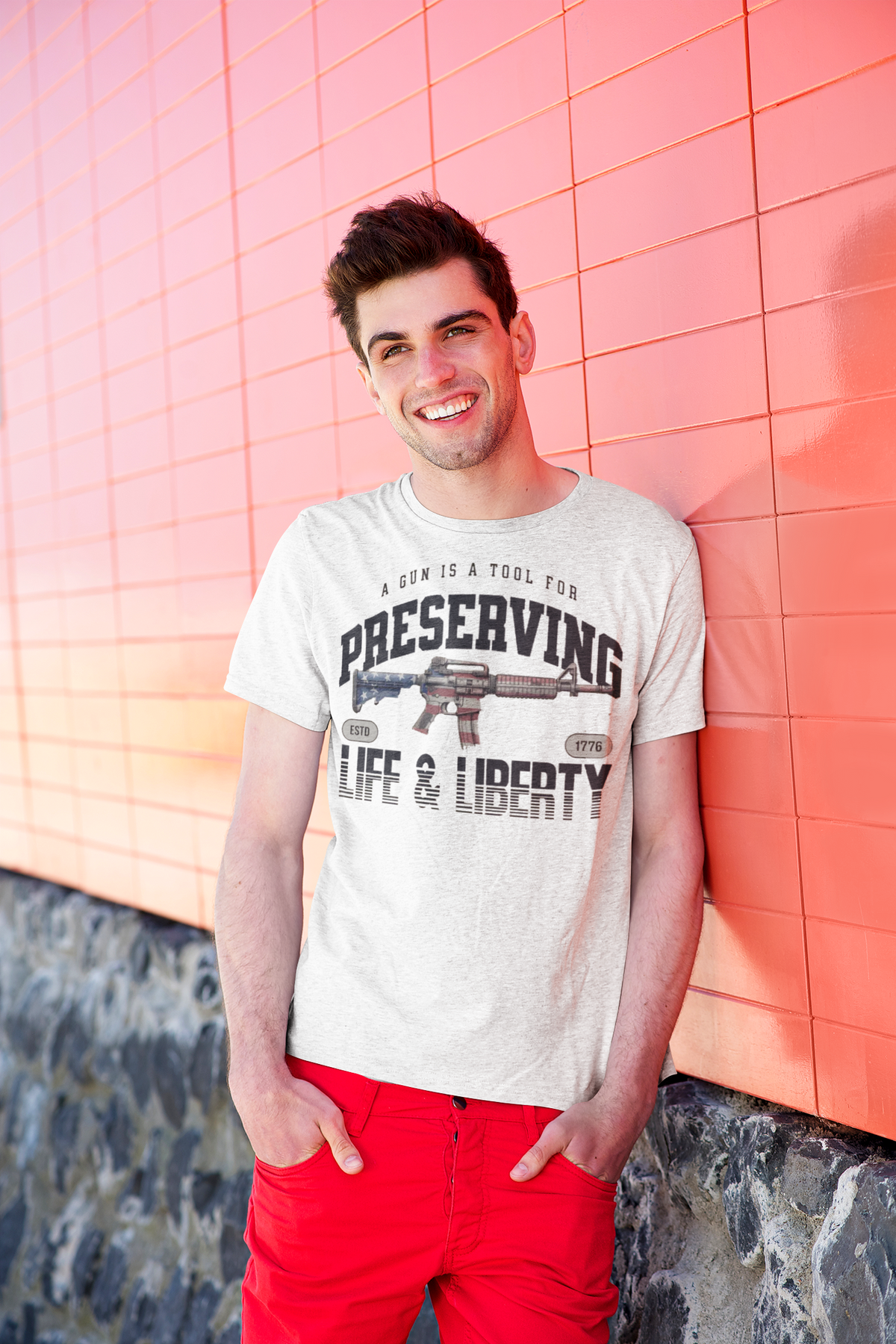 A Gun Is A Tool For Preserving Life and Liberty graphic tee worn by a smiling man against a colorful background.