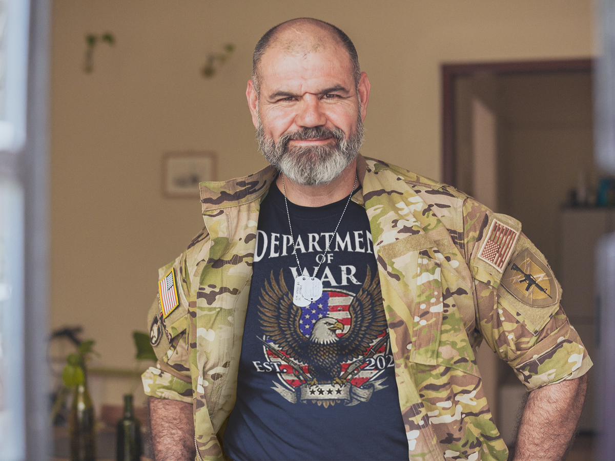 Man wearing a camouflage jacket and Department Of War Graphic Design t-shirt, showcasing patriotism and national pride.