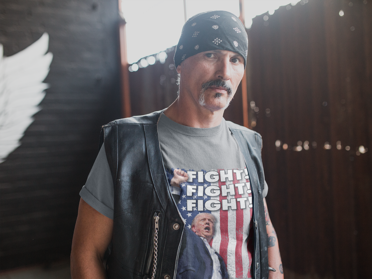 Man wearing a leather vest and a Fight Fight Fight Bold Logo Tee, standing in an industrial space.