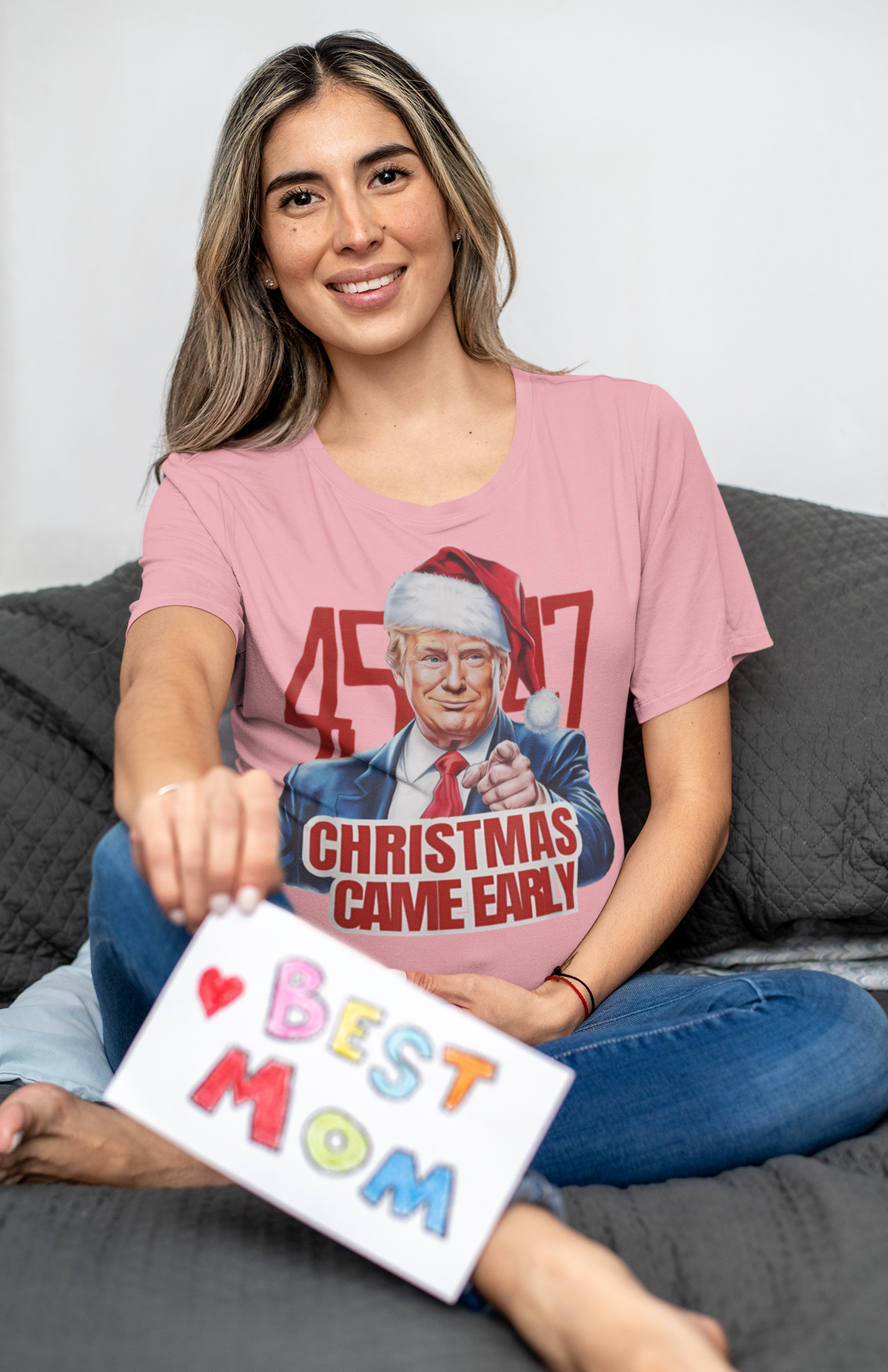 Woman wearing Christmas Came Early 45 47 Gear graphic t-shirt, holding a colorful 'Best Mom' card.