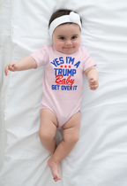 Yes I am A Trump Baby Onesie Art displayed on a baby wearing a pink onesie with a cute headband on a white sheet.