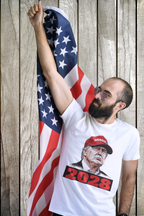 Man proudly wearing Trump Maga 2028 Visionary Gear tee, raising fist with American flag in background.