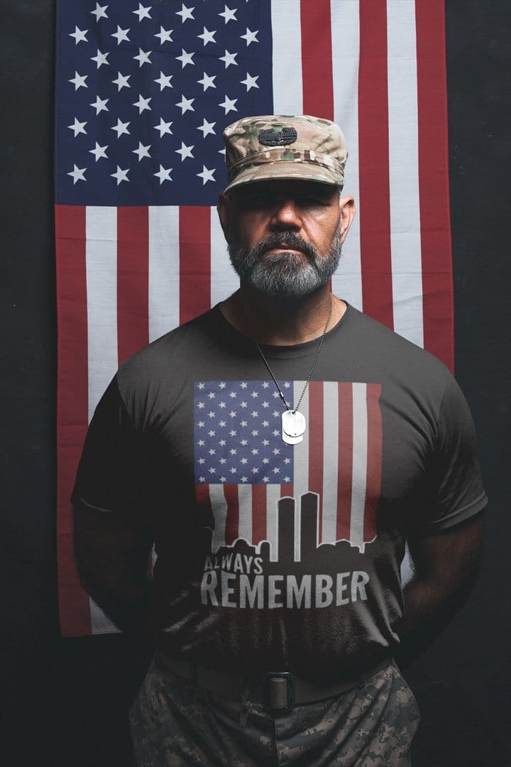 Man wearing 'Always Remember Twin Towers On American Flag' tee standing in front of American flag.