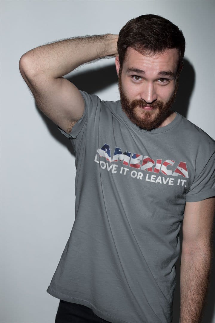 Man wearing America Love It Or Leave It Classic Statement Tee Shirt with patriotic design, posing confidently against a white background.
