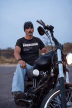 Man wearing Ammosexual Sarcastic Graphic Design tee sitting on a motorcycle in an outdoor setting.