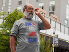 Man wearing God Guns Trump With American Flag graphic tee standing outdoors.