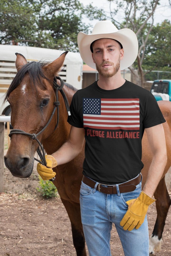 Man wearing 'I Pledge Allegiance With American Flag' t-shirt holding a horse, showcasing conservative values.