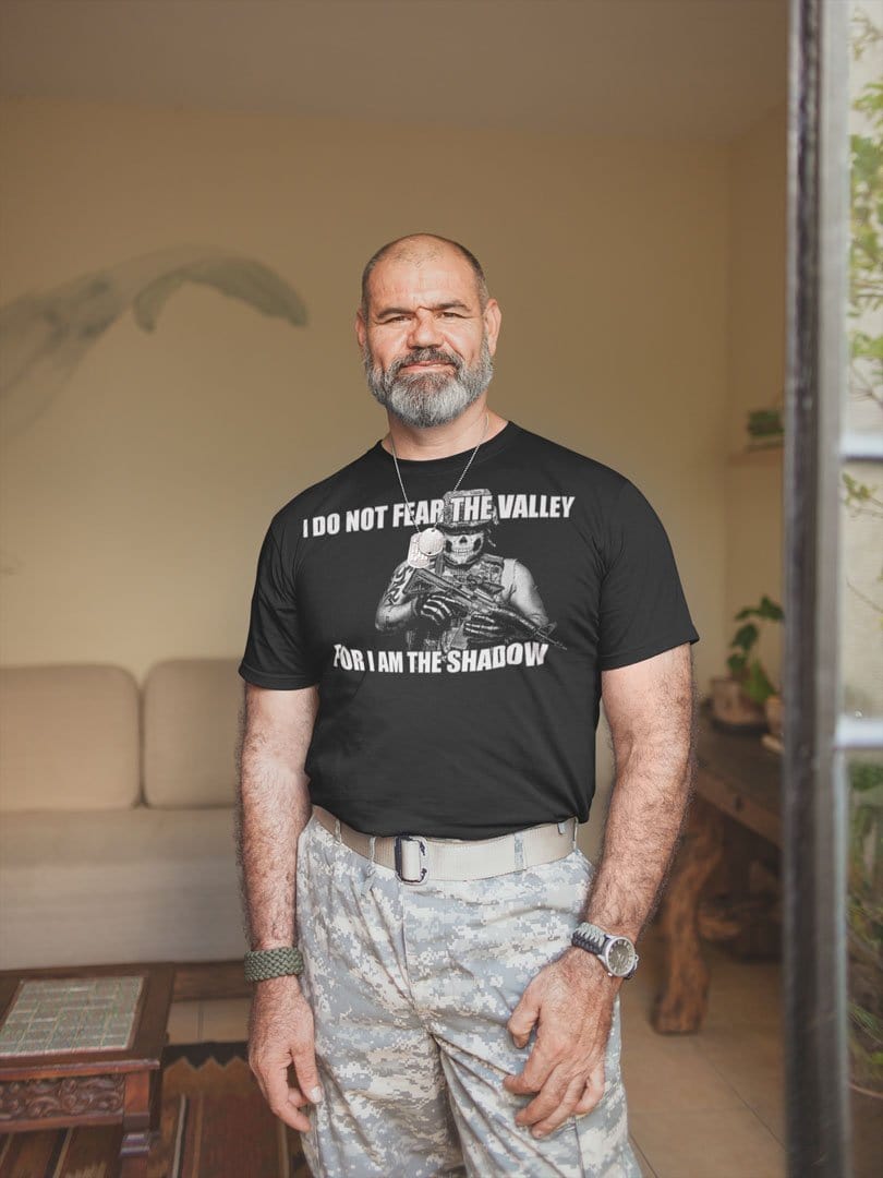 Man wearing "I Do Not Fear The Valley For I Am The Shadow" graphic tee in a living room.