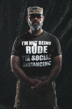 Man wearing I'm Not Being Rude I'm Social Distancing shirt in military-style setting.