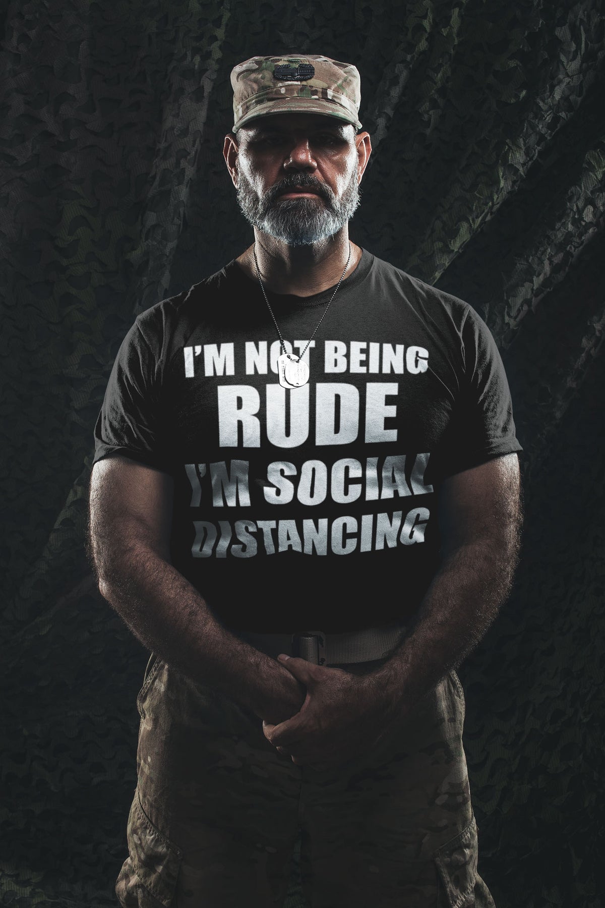 Man wearing I'm Not Being Rude I'm Social Distancing shirt in military-style setting.