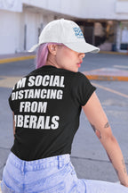 Person wearing I'm Social Distancing From Liberals Blk On Back t-shirt with bold statement in urban setting