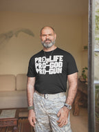 Man wearing a black typography statement graphic tee with bold lettering inside a cozy living room.