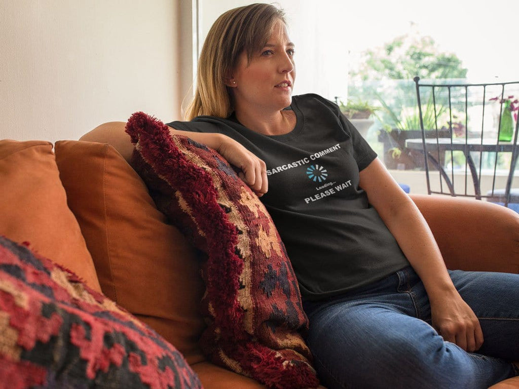 Woman wearing 'Sarcastic Comment Loading Please Wait Design' t-shirt, sitting on a couch with a relaxed expression.