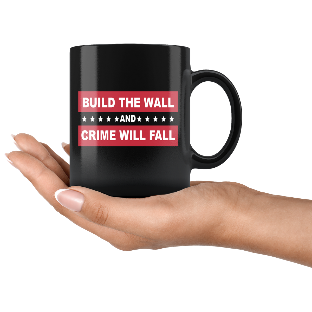 Hand holding Border Security Equals Safer Land black mug with 'Build The Wall And Crime Will Fall' text.